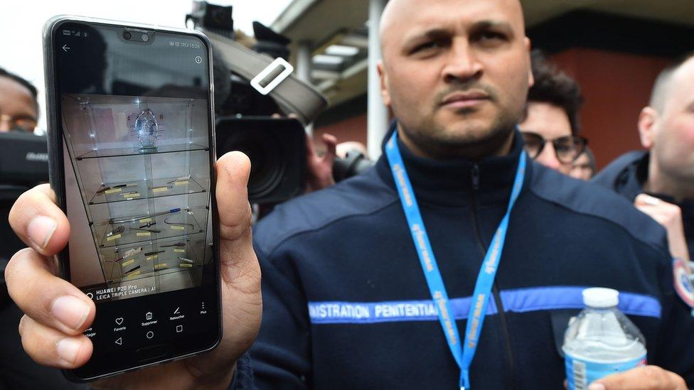 A prison guard shows to the press prohibited items found in prison cells for a year at the penitentiary center of Alencon, in Conde-sur-Sarthe