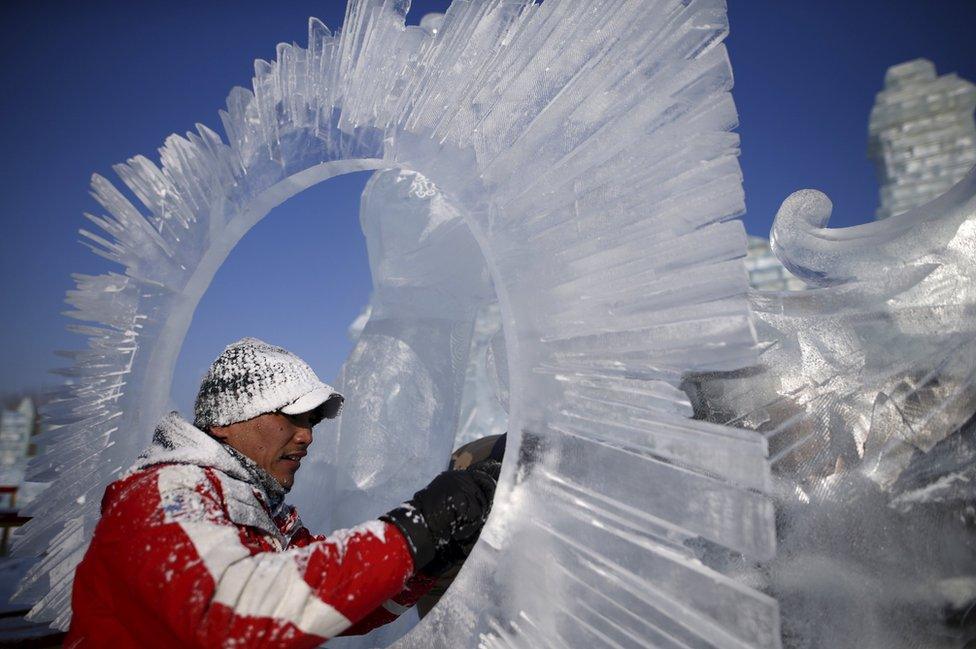 A worker polishes an ice sculpture