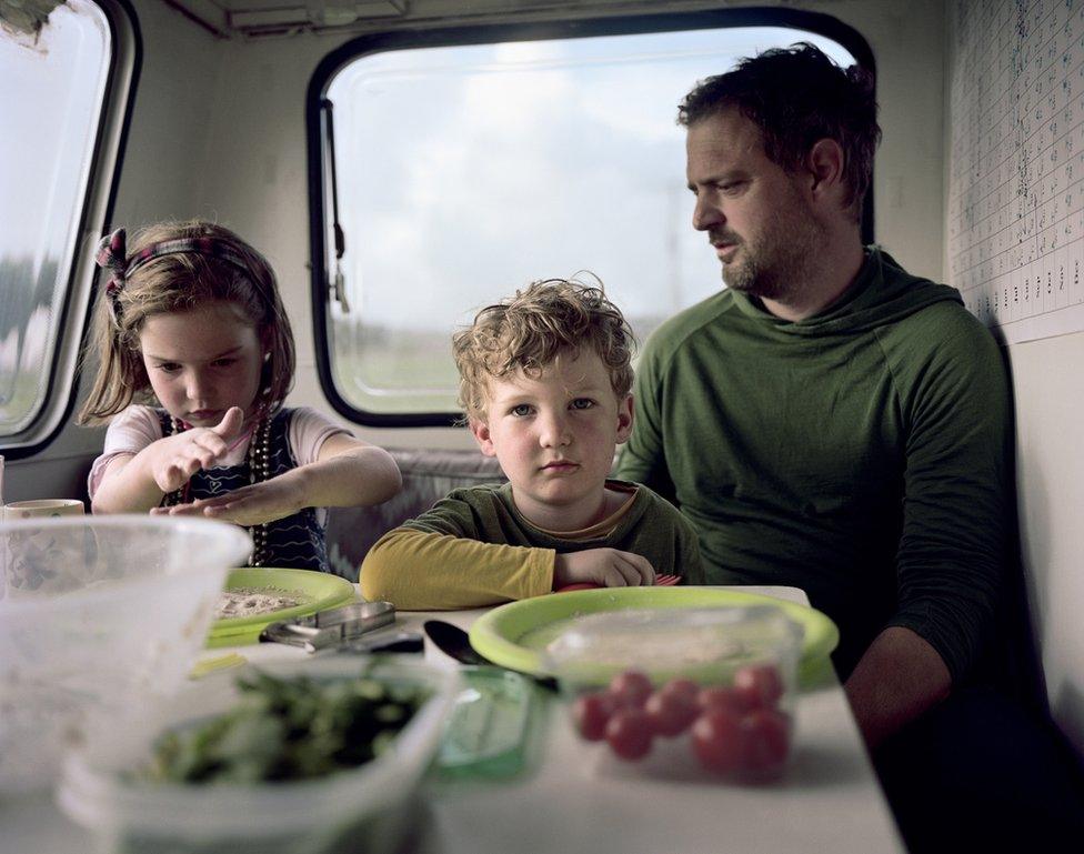 A family sit in their caravan.