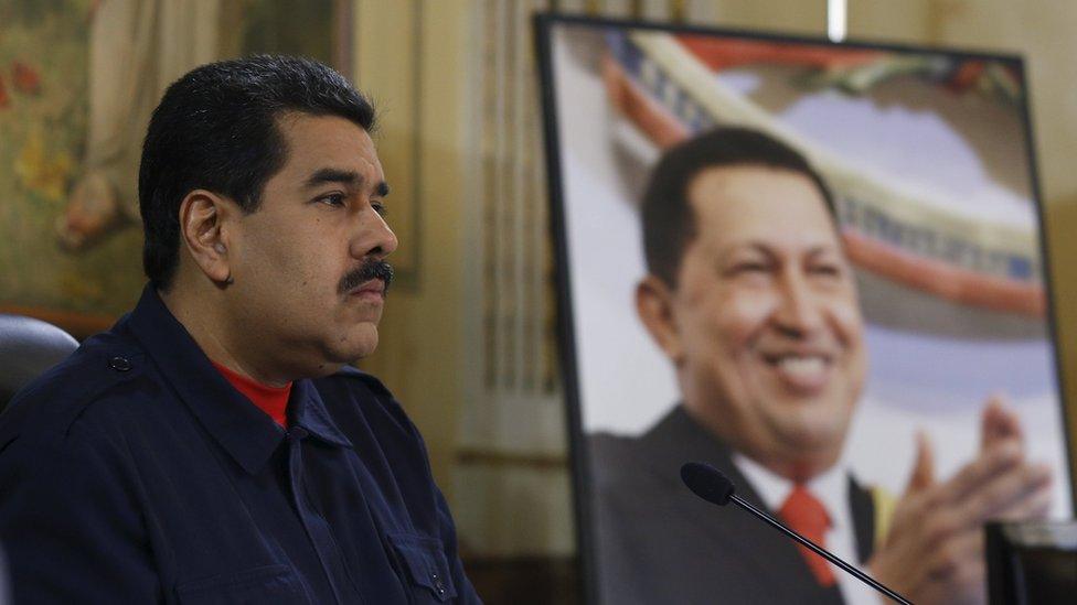 Venezuela's President Nicolas Maduro speaks next to a picture of late President Hugo Chavez