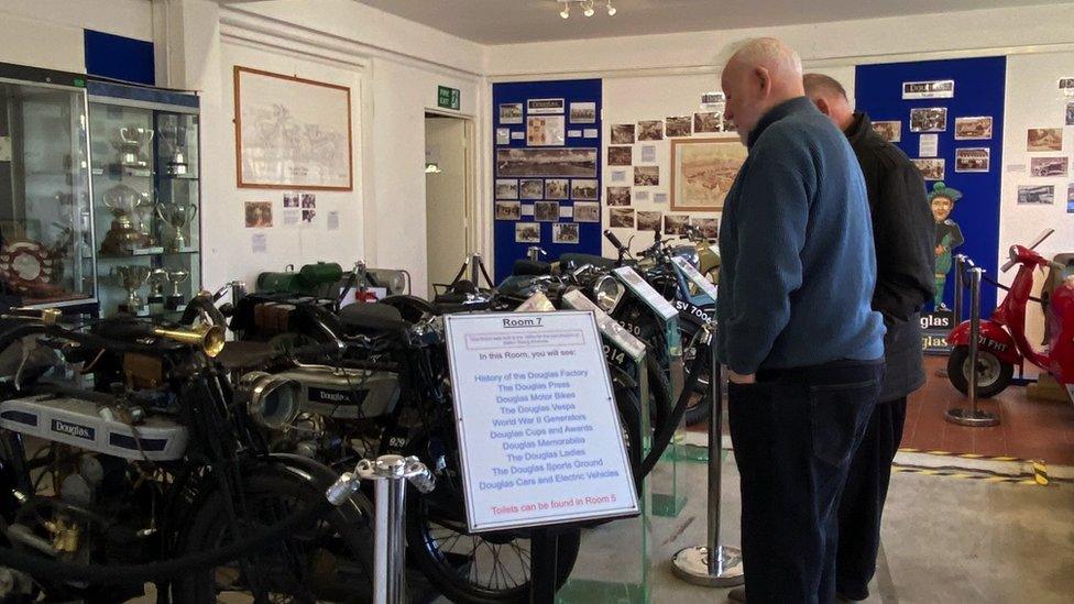 Image of people looking at an exhibit featuring motorbikes