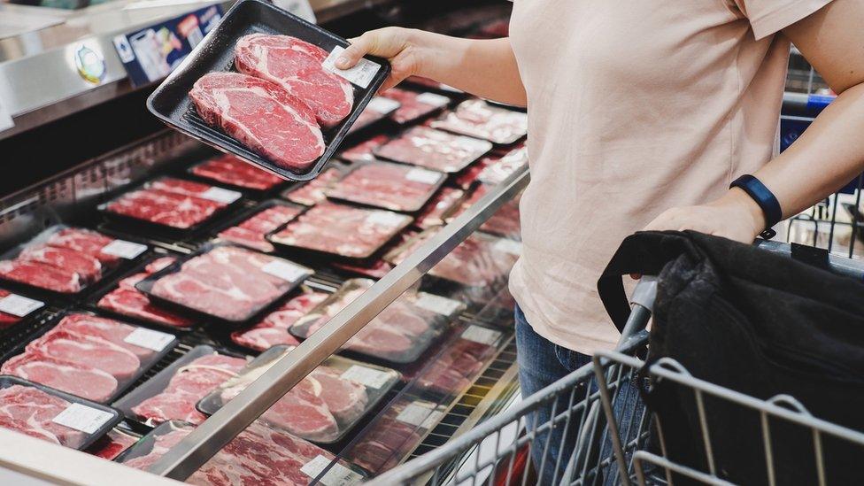 Woman shopping at meat section in supermarket.