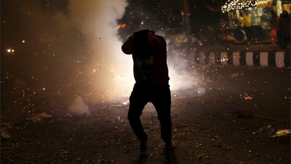 A man tries to protect himself from firecrackers while celebrating the Hindu festival of Diwali, the annual festival of lights in New Delhi, India, November 11, 2015