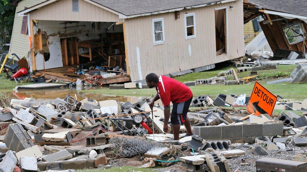 A resident sorts through debris as the cleanup begins from severe flooding in West Virginia on 24 June