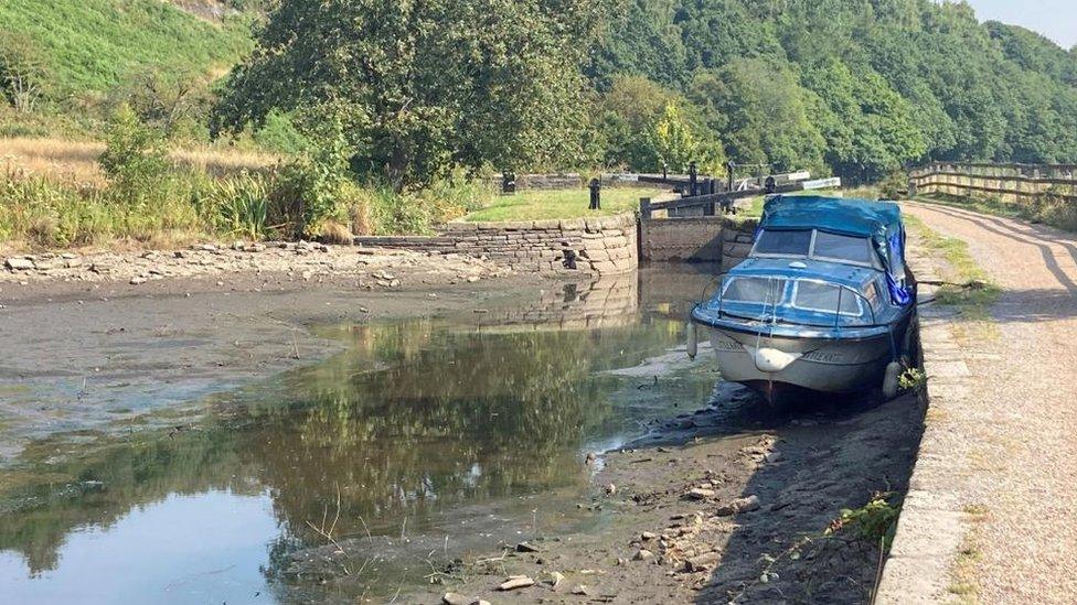 A boat sits in the dried up Huddersfield narrow canal in West Yorkshire