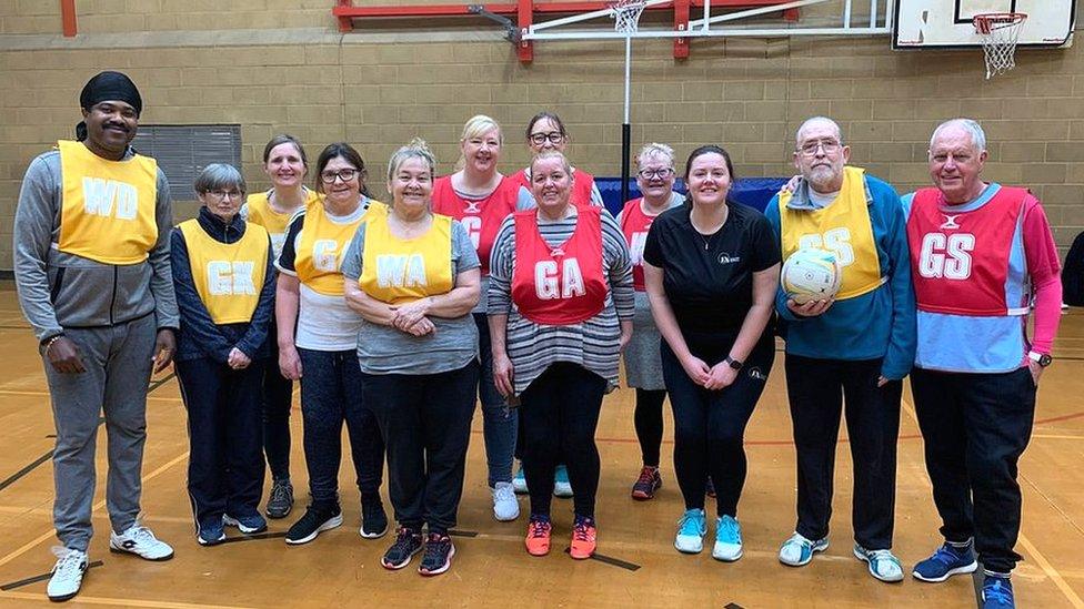 Netball players gathered for photo, wearing red and yellow bibs.