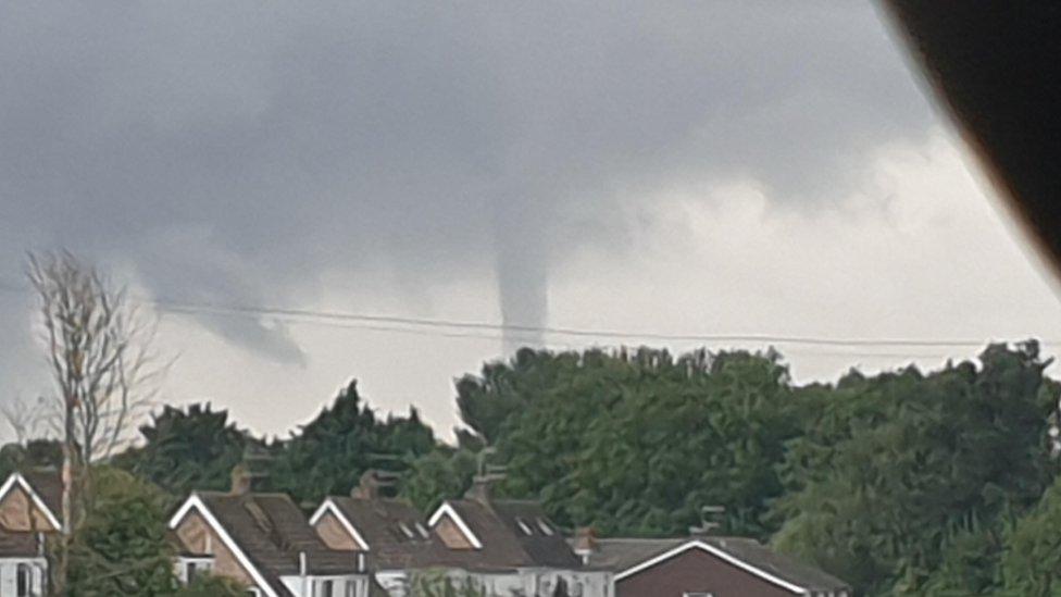 Large tornado cloud seen behind houses