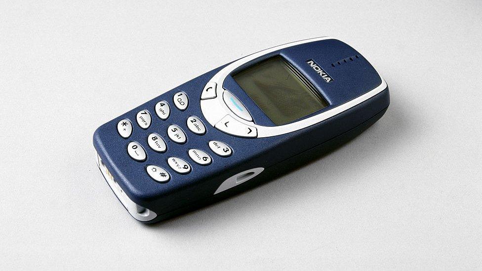 a nokia 3310 phone lying on a white surface