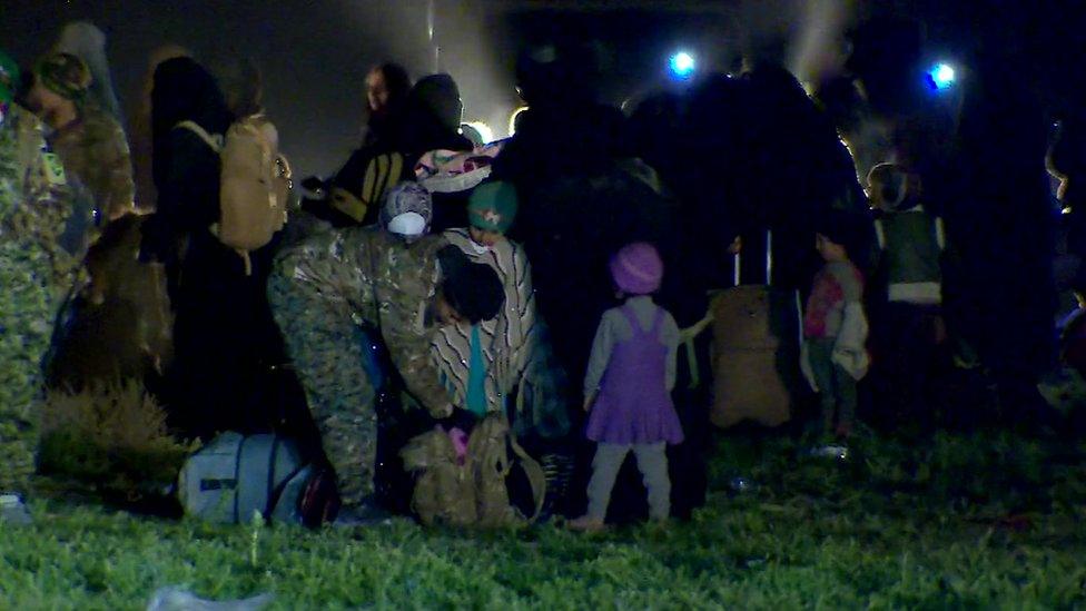 Children and women with their belongings under nightfall