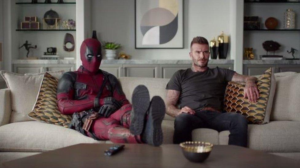 Deadpool and David Beckham watching TV