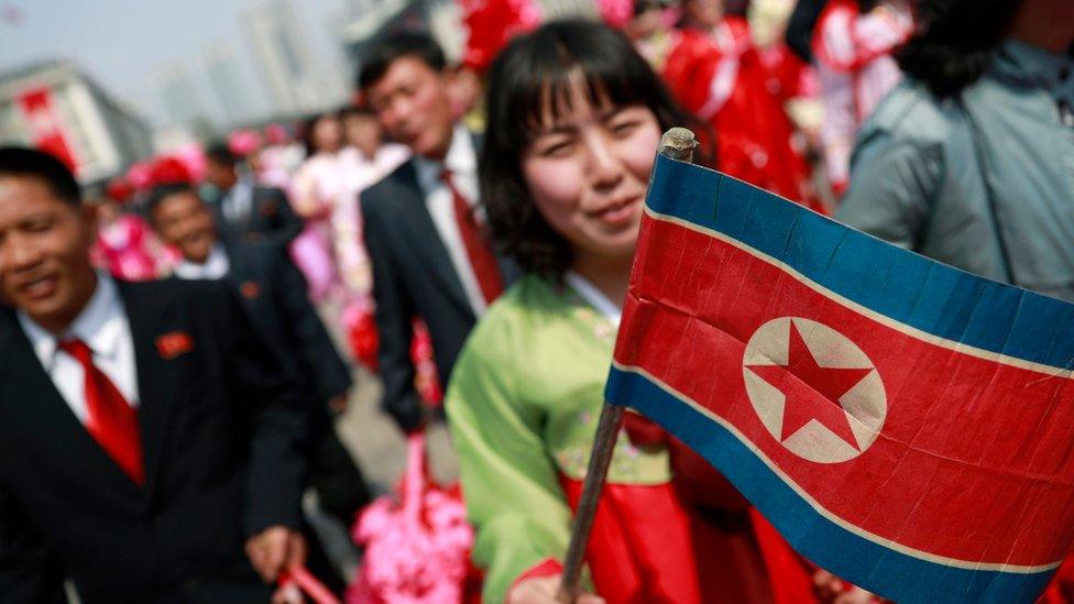 A North Korean woman carries the national flag after a parade for the 'Day of the Sun' festival