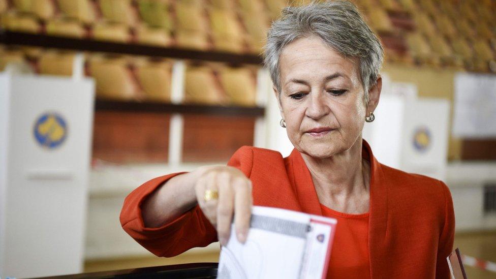 A woman casts her ballot at the polling station in Pristina