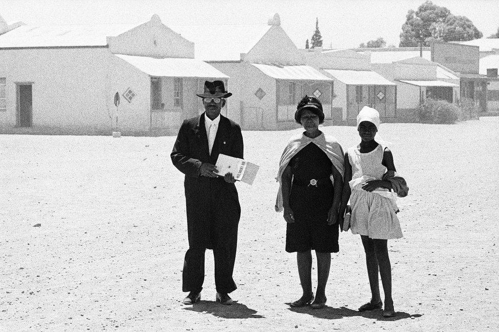 An elder of the Dutch Reformed Church walking home with his family after the Sunday service, Carnavon, Cape Province (Northern Cape), January 1968.