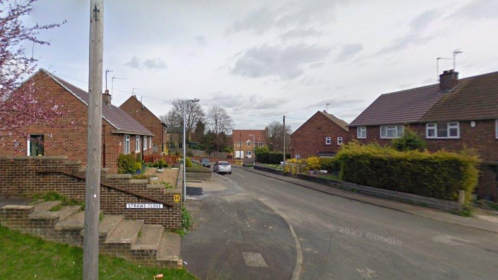 Residential street with brick-built houses and "Straws Close" sign