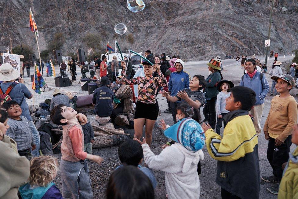 A young girl blows bubbles to entertain children during a cultural day at the roadblock in Purmamarca, Jujuy province, Argentina, June 25, 2023.