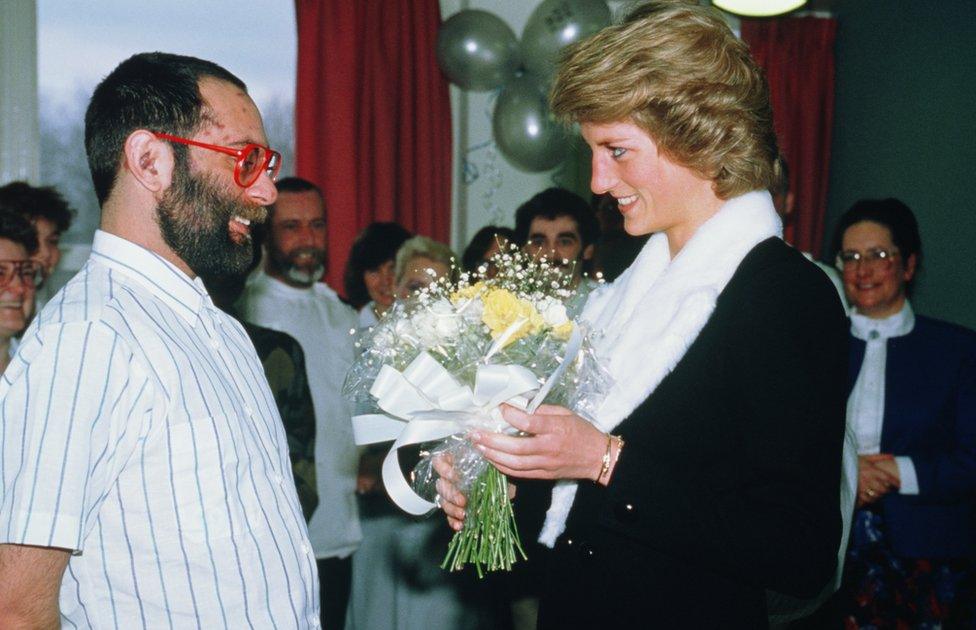 Princess Diana speaks to a patient whilst holding flowers