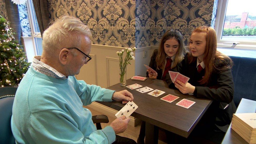 School pupils playing cards with a care home resident