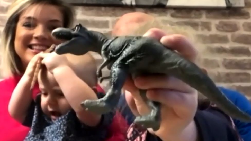 lily-who-found-dinosaur-print-on-beach-with-her-parents-holding-up-her-toy-dinosaur