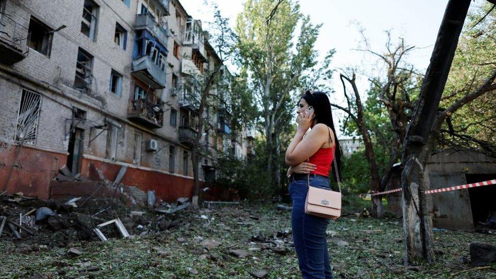 A woman on her mobile phone near wreckage in Ukraine