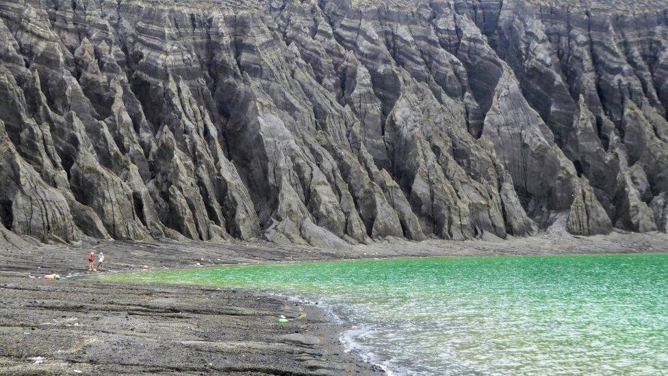 The cliffs of the crater lake are etched with erosion gullies