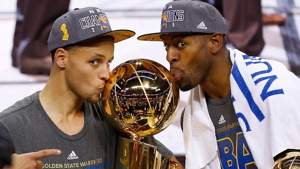 Golden State Warriors Stephen Curry, left, and Andre Iguodala kiss with the Larry O'Brien Trophy after defeating the Cleveland Cavaliers 105-7 in Game 6 of basketball's NBA Finals in Cleveland.