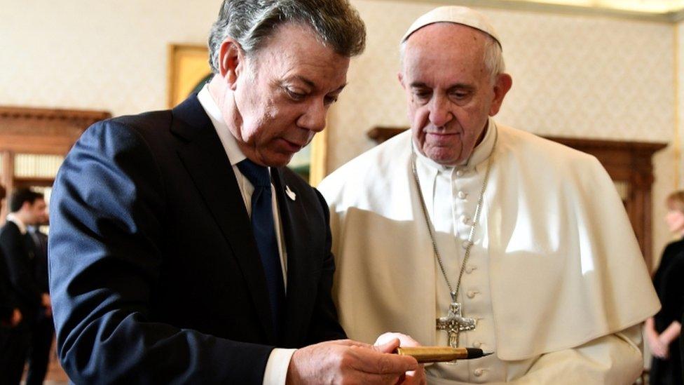 Colombian President Juan Manuel Santos reads to Pope Francis, as they meet at the Vatican, Friday, Dec. 16, 2016