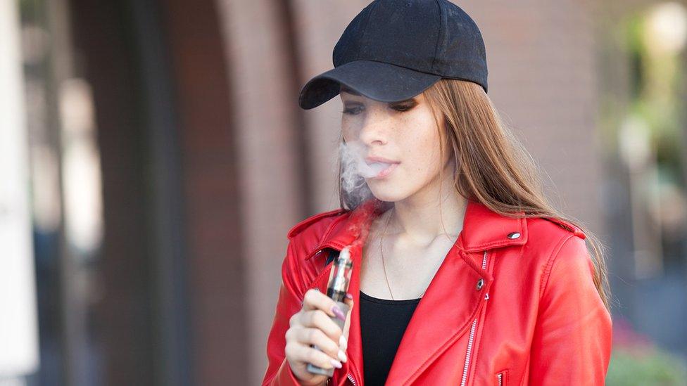 Young woman vaping on the street