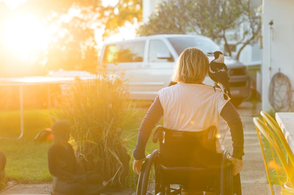 Sam Bloom in her wheelchair with Penguin on her shoulder