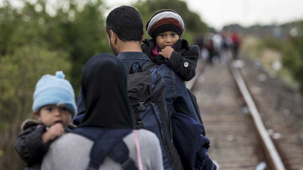 A family from Syria walks along rail tracks in Hungary