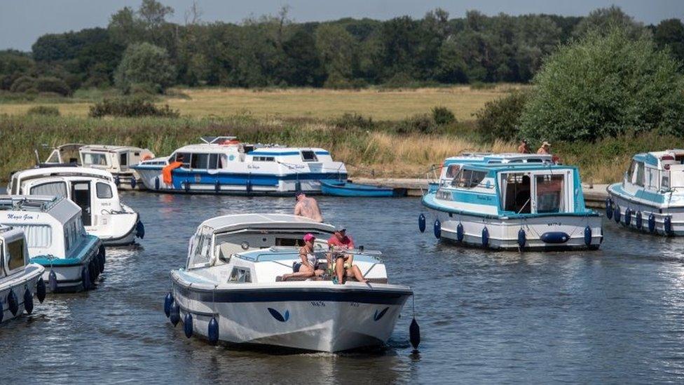 Pleasure boats make their way along the River Ant at Ludham Bridge on The Broads in Norfolk