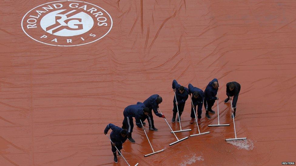 Rain being swept off tennis court