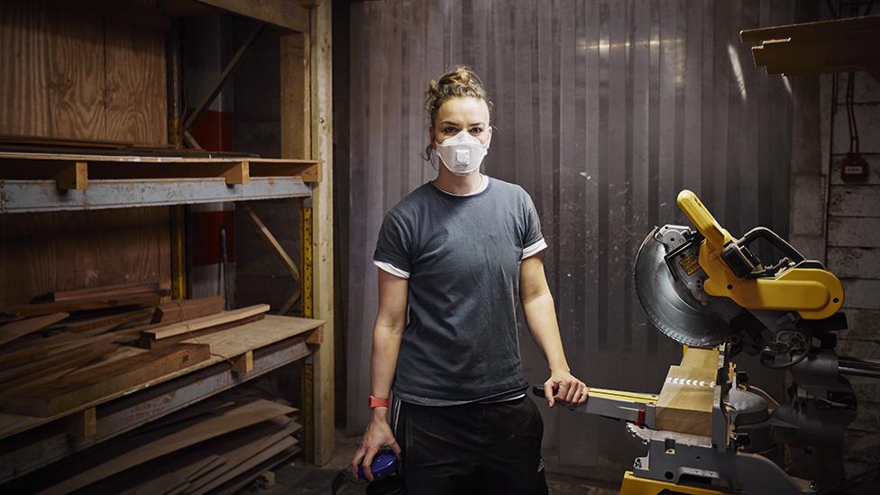 Woman with mask working in carpentry workshop