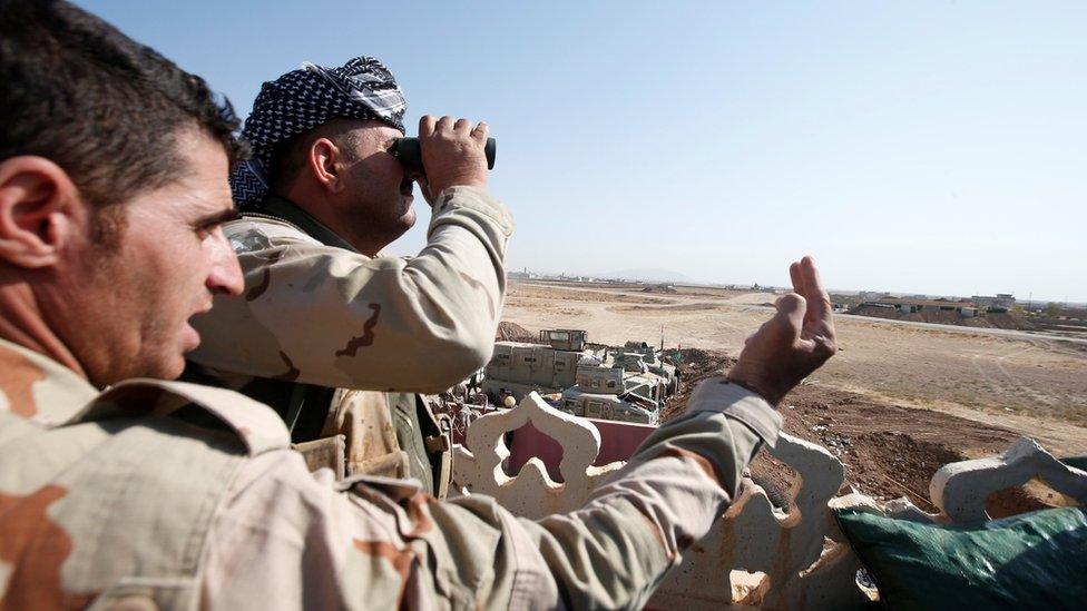 A Kurdish Peshmerga fighter looks through a pair of binoculars on the outskirts of Bashiqa, east of Mosul (30 October 2016)