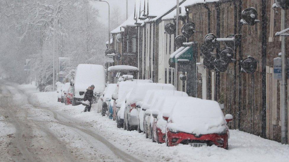 A motorist brushes snow off a car in Braco near Dunblane