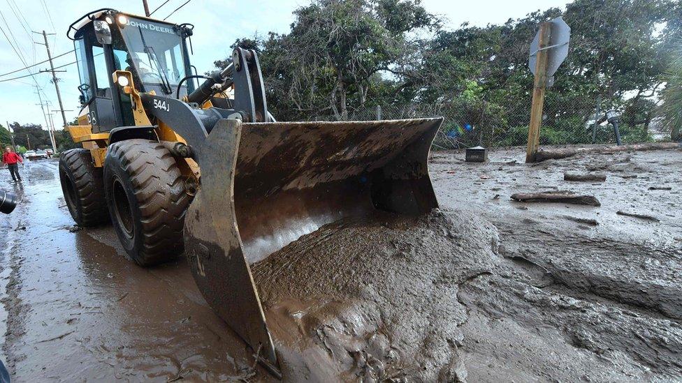 A bulldozer clears mud off the road near a flooded section of US Highway 101 near the San Ysidro exit in Montecito, California.