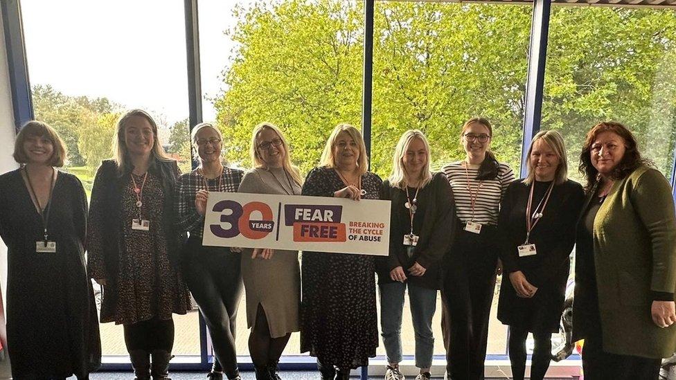 Staff standing together in front of a window holding a FearFree banner