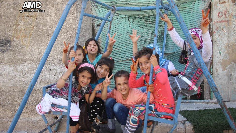 Children sit on swings in Aleppo