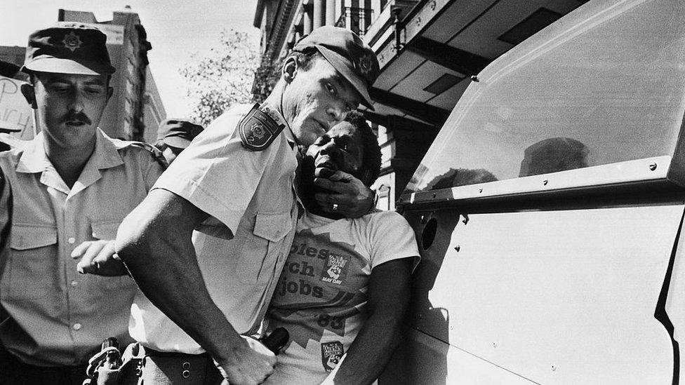 South African police officers aggressively arrest Moses Mayekiso, a prominent trade union leader, during a protest march in Johannesburg, South Africa (archive shot)