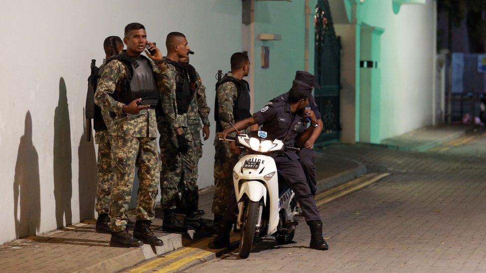 Nov. 2, 2015 photo, Maldivian security officers stand guard near the president's official residence where the military say they found and deactivated an explosive device in Male.