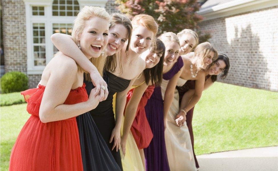 A group of female high school students outside in their prom dresses