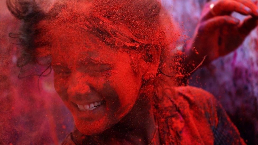 A girl is covered in red paint powder