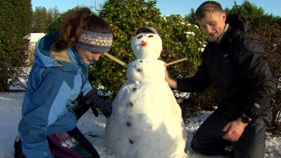 Two people building a snow man