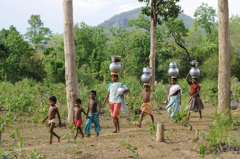 Indian women and children of the Gothikoya or Muria Gond tribe from Maoist insurgency-hit Chhattisgarh state walk 3 km for drinking water from their temporary abodes inside the forest terrain of Khammam district, about 450 km from Hyderabad, on July 2, 2009.