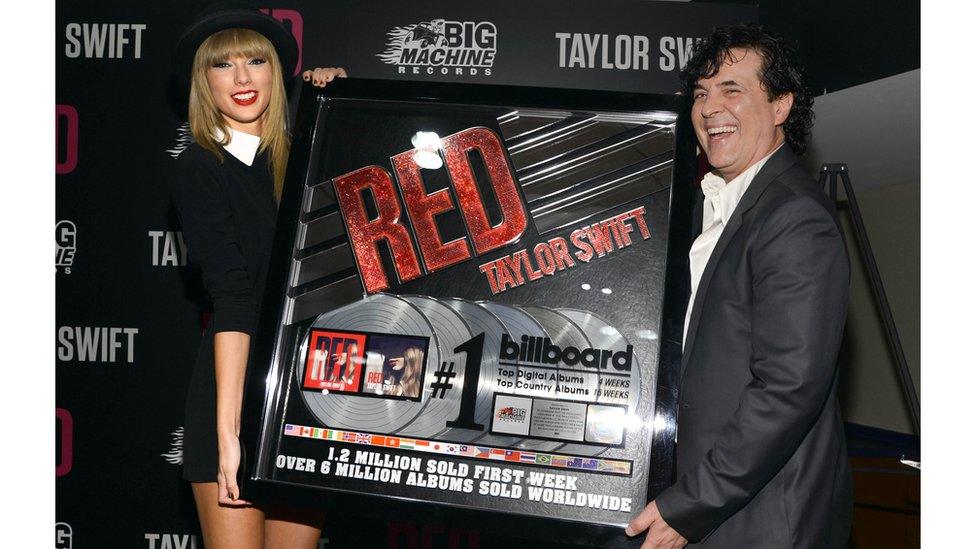 taylor swift and scott borchetta celebrate red going platinum holding a massive plaque