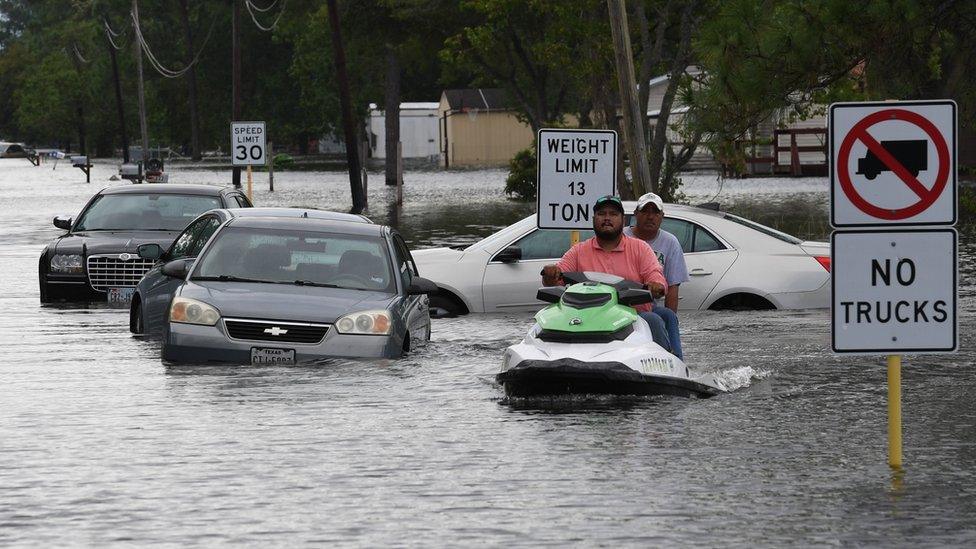 Locals jet ski through the flooded streets in Crosby, Texas, 30 Aug 2017