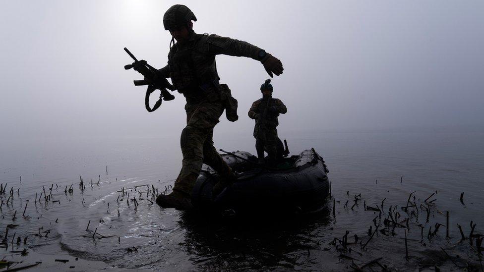 A Ukrainian serviceman jumps out of the boat on the shore of Dnipro river at the frontline near Kherson, Ukraine, Sunday Oct. 15, 2023.