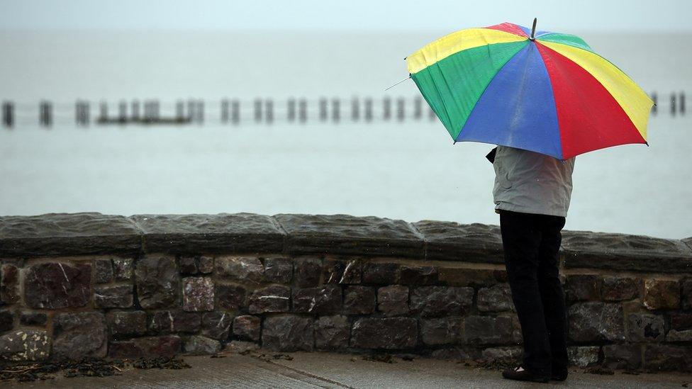 Woman shelters under umbrella