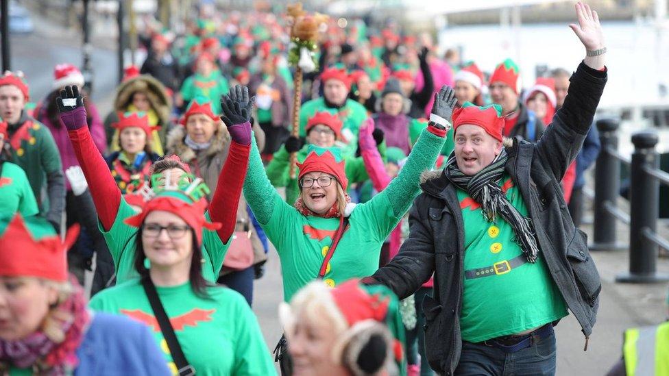 People dressed as elves walk on the riverside