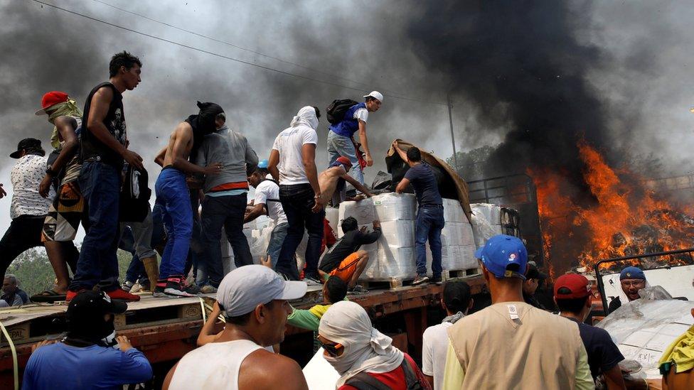 Opposition supporters unload humanitarian aid from a truck that was set on fire after clashes between opposition supporters and Venezuela's security forces at Francisco de Paula Santander bridge on the border between Colombia and Venezuela as seen from Cucuta,