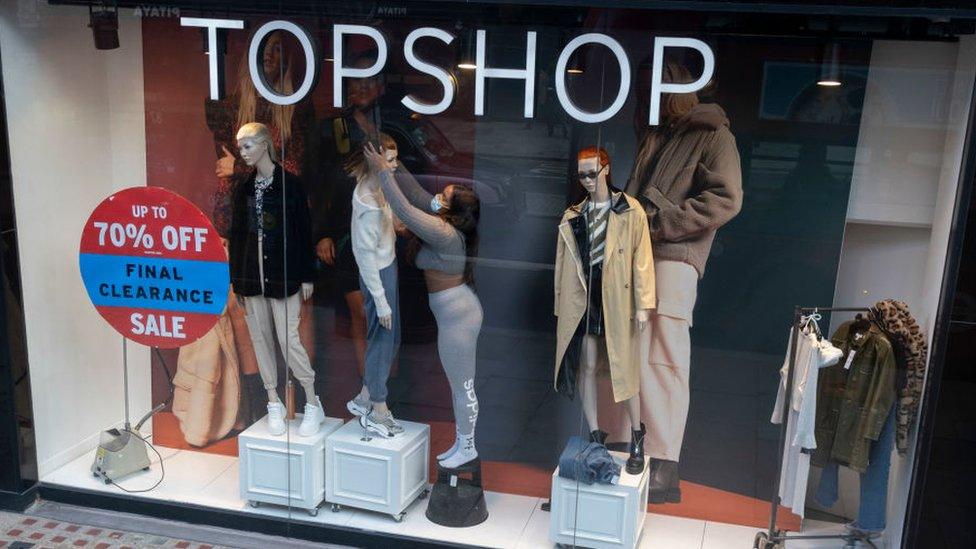 Woman in mask dresses Topshop window